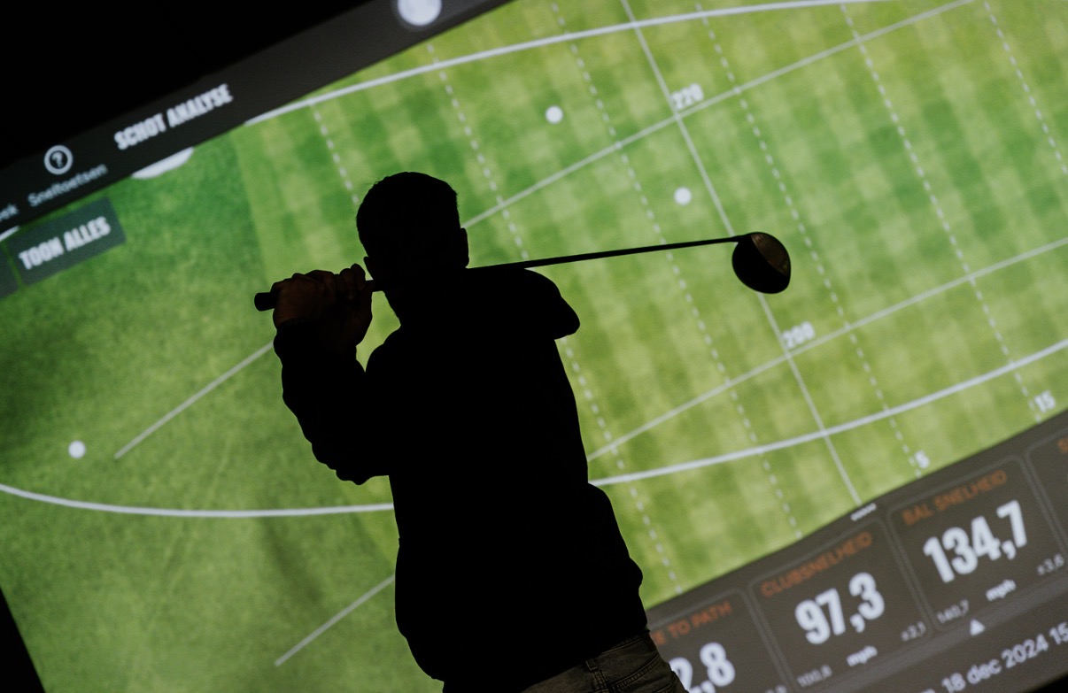 Golfer die afslaat voor een indoor golfsimulator